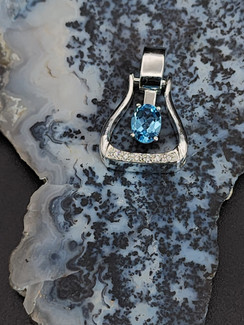 A western stirrup in sterling silver featuring a vibrant AAA Swiss blue topaz in the middle. This piece has on the lower border of the stirrup a line of cz to give it that extra bling. A row or hearts line the side of this special stirrup
