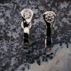 Horseshoe nail hooped earrings. A different take on a traditional equine accessory.  The horseshoe nail is bent back to form a circle from behind. It is secured with a post and a cubic zirconium that is set in the top of the nail. Available in silver and gold with any gemstone. Just notify me of any customization. 8593330458.