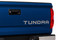 Rear tailgate of blue Toyota Tundra truck showing silver metallic letter and text decals.
