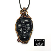 Front view of Carved Black Agate pendant necklace in raw copper with deep red Garnets