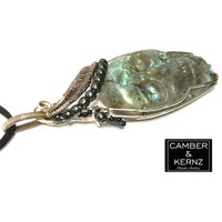 Side view of carved labradorite skull with hematite and black agates on a black suede cord