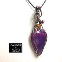 Front view of pear shaped Dragon Vein agate with purple pearls and orange carnelian showing reflections of light