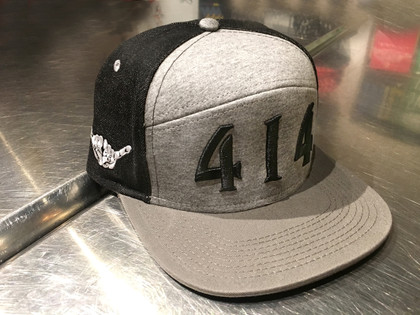 Walk down the high street with this 414 fashion hat. 96% breathable cotton denim high crown hat. Structured square visor in black. Heather heritage flannel front panel 4% acrylic. Milwaukee skyline print under visor. Adjustable snapback hat.