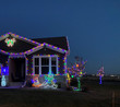 A house covered in lights with a snowman light display in front.