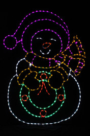 LED light display of a snow lady with a yellow scarf and mittens, a purple hat, who is holding a green wreathe with a red bow and berries 