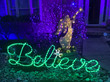 A house with a "believe" light sign in the yard.