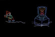 Animated LED light display of a orange reindeer driving a blue snow plow with an elf dressed in green and red getting ready to throw a snowball at the plow