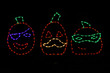 LED light display of three jack-o-lanterns, one has a purple eye patch, one has a yellow mustache, and one has a green eye mask