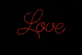 An LED holiday wireframe decoration reading "Love" in red cursive. 