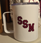 White stainless steel 15oz mug featuring SSM in Maroon lettering. Clear plastic lid included.