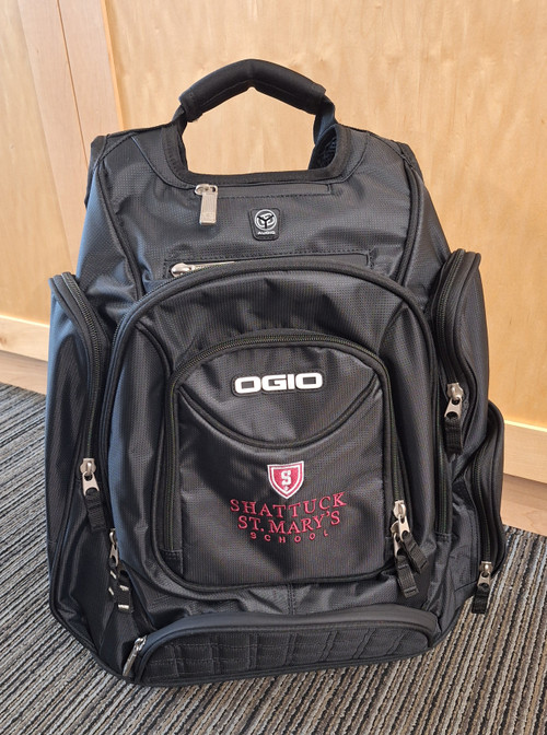 Ogio Metro backpack features back panel side-entry padded laptop pocket, large center storage area. Power cord and mouse storage, internal file sleeve. Weatherproof fleece-lined digital media/audio pockets with headphone exit port,. Adjustable sternum strap, deluxe organization panel. Features new Shattuck St. Mary's logo on front.

 