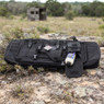 Nuprol Premium Padded Airsoft Rifle Bag 36" in Black on rocky ground, with an open pocket holding BBs