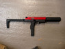 The VORSK VMP-1X SMG Gas BlowBack Semi Auto Only SMG in Black/Red shown from the right on a textured surface. The VORSK VMP-1X SMG Gas BlowBack Semi Auto Only SMG in Black/Red shown from the right on a textured surface.