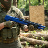 Player holding the Double Eagle M309 Pump Action Shotgun in Blue during an outdoor airsoft game.