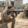 A player in camo gear kneeling and aiming the Cyma CM615 AEG Keymod hand-guard Rifle In blue at an outdoor field. A player in camo gear kneeling and aiming the Cyma CM615 AEG Keymod hand-guard Rifle In blue at an outdoor field.