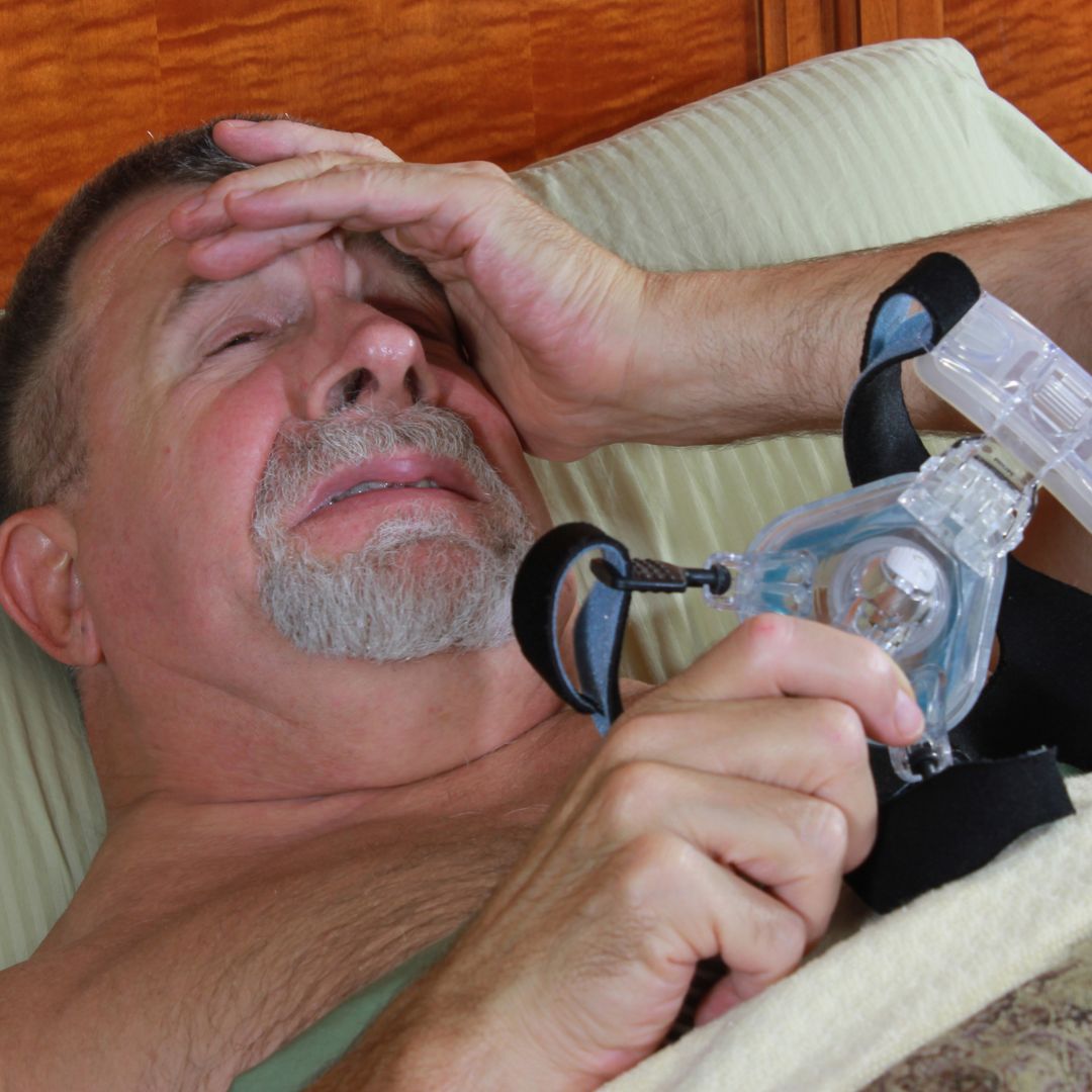 Man having difficulty sleeping with CPAP mask on