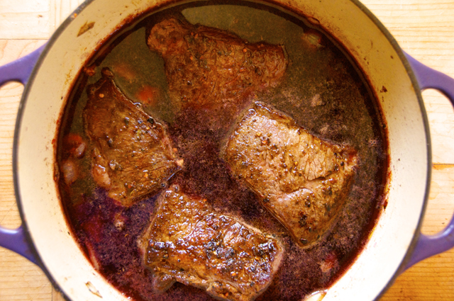 pour red wine and broth with boneless short rib in dutch oven