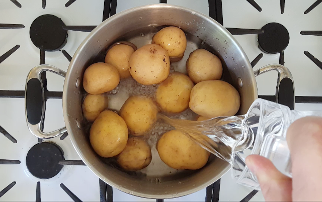 picture of water being poured into a pot of potatoes