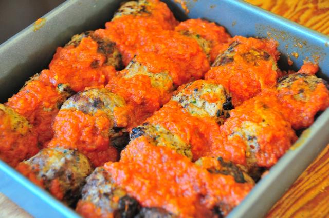 browned meatballs in a baking dish covered in tomato sauce