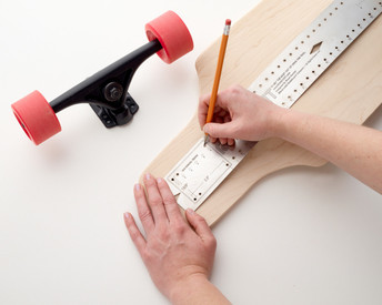 Find your centre line, mark truck hole patterns and distances, draw long straight lines. This ruler bends along the 3-dimensional shapes of your skateboard.