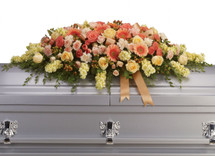 The beautiful casket floral arrangement or cover  includes peach roses, light pink spray roses, coral spray roses, light orange gerberas, light orange carnations, light yellow stock and peach hypericum, accented with satin ribbon and assorted greenery.