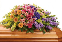 The elegant arrangement includes purple hydrangea, hot pink roses, peach spray roses, pink stargazer lilies, peach miniature gerberas, green gladioli, pink carnations, yellow snapdragons, lavender stock and solidago, accented with assorted greenery.