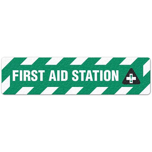 Photograph of an anti-slip floor safety sign reading "First Aid Station" in white on a green background.  Includes a graphic of a white cross within a black triangle.