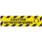Photograph of an anti-slip floor safety sign reading "Caution Ear Protection Required" in black on a yellow background.  Includes a graphic of a head wearing ear muffs.