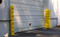 A photograph of yellow 02241 eagle corner protectors, set of two 42" height installed outdoors on corners.