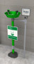 A photo illustration of a Guardian GFR1825GRN Freeze-Resistant Eyewash with a green plastic bowl installed next to a cinderblock wall.