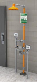 A photograph of a Guardian GFR1902SSH Freeze-Resistant Safety Station with Eyewash and stainless steel bowl installed next to a cinderblock wall.