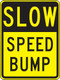 A photograph of a black and yellow 06250 speed bump sign, reading slow speed bump.