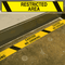 A photograph of a yellow and black 06457 printed warning tape, installed on floor of a facility.