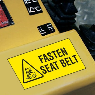 A photograph of a yellow 12205 forklift label, reading fasten seat belt with graphic installed on machinery.