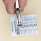 A photograph of a person punching a metal tag with a 09873 heavy duty hole punch showing the convenient viewing window.