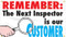 Picture of Workplace Safety Banner that features a clean white background. In the bottom left is a hand holding a magnifying glass up to the text on the banner. Along the top of banner in bold eye-catching red it reads "Remember:", continued below in bold black text it reads "The next inspector is our", and finished off in cool blue text it reads "Customer". The text combined reads out "Remember: the next inspector is our customer"