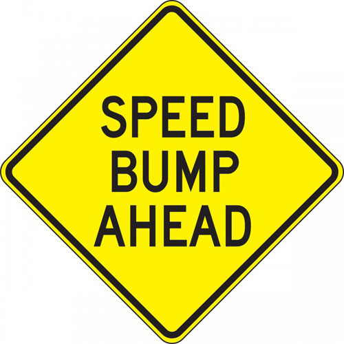 A photograph of a yellow and black 06256 speed bump sign, reading speed bump ahead.