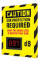 A photograph of a yellow and black 11104 OSHA caution industrial decibel meter sign, reading ear protection required when the sound level is greater than 85 dB, and dimensions 12" l x 10" w.