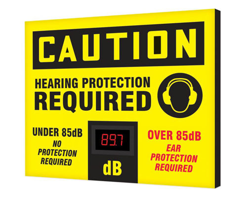 A photograph of a yellow and black 11107 OSHA caution industrial decibel meter sign, reading hearing protection required, and dimensions 20" x 24" .