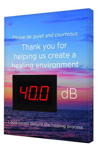 A photograph of a blue 11110 healthcare decibel meter sign, reading please be quiet and courteous, with sunset  graphic, and dimensions 12" x 10".