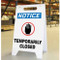 A photograph a white A-Frame Standing Floor sign, standing upright. The front face has an OSHA NOTICE header, a black hand icon with red circle, and the words TEMPORARILY CLOSED.