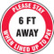 A photograph of a red and white 11226 social distance floor sign, reading please stay 6 ft away when lined up to pay.