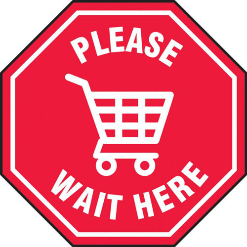 A photograph of a red and white 11234 social distance floor sign, reading please wait here, with shopping cart icon.