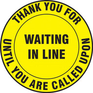A photograph of a yellow and black 11241 social distance floor sign, reading thank you for waiting in line until you are called upon.