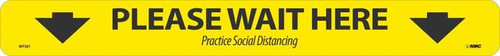 A photograph of a yellow and black 05422 please wait here | practice social distancing removable social distance floor sign.