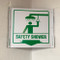 Example of a similar sign (safety shower) mounted on the inside corner of a cinderblock wall.
