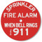 This red plastic sign  has white lettering that reads "SPRINKLER FIRE ALARM.  WHEN BELL RINGS DIAL 911."
