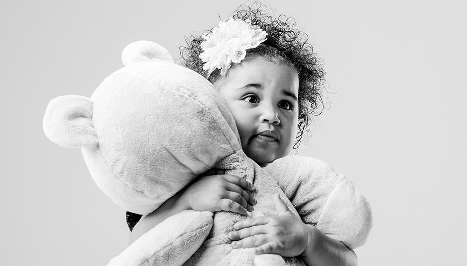 Adorable little girl cuddling teddy bear picture in black and white by Emotion Studios. 