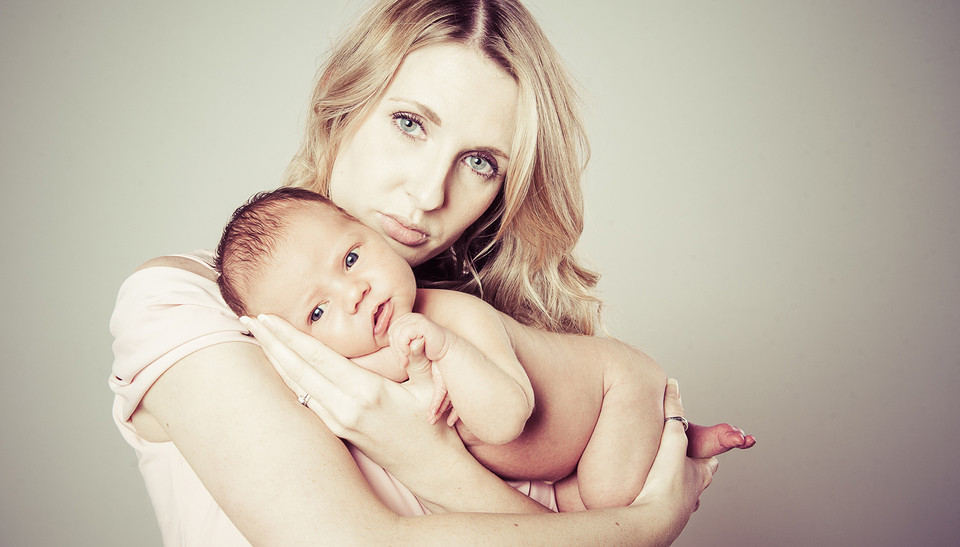 mother holding newborn baby girl in studio photograph