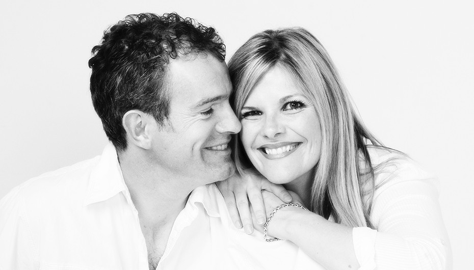 Photograph of a happy couple smiling. Image in black and white, photographed by Emotion Studios.